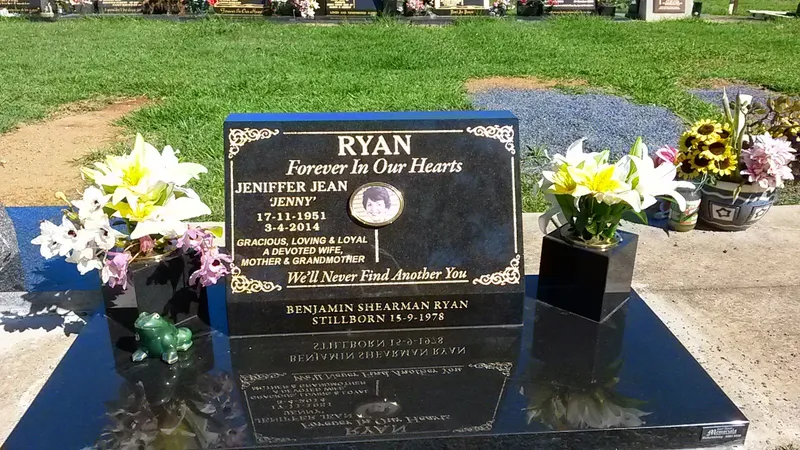 Black granite monument with gold lettering, a photo plaque and vases