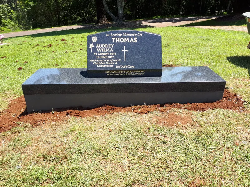 Black granite headstone with an engraved cross on a wide black base