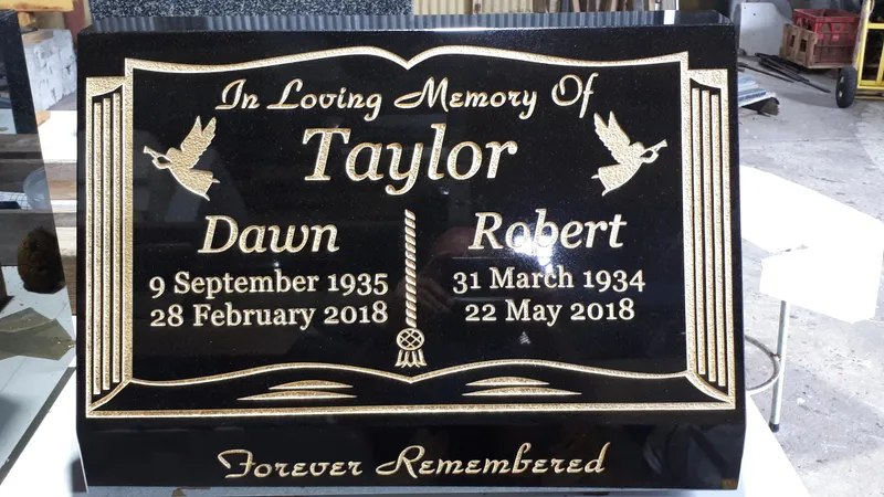 Black granite open-book plaque with gold lettering and doves