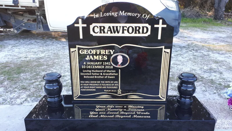Black granite headstone with gold crosses and matching black granite urns