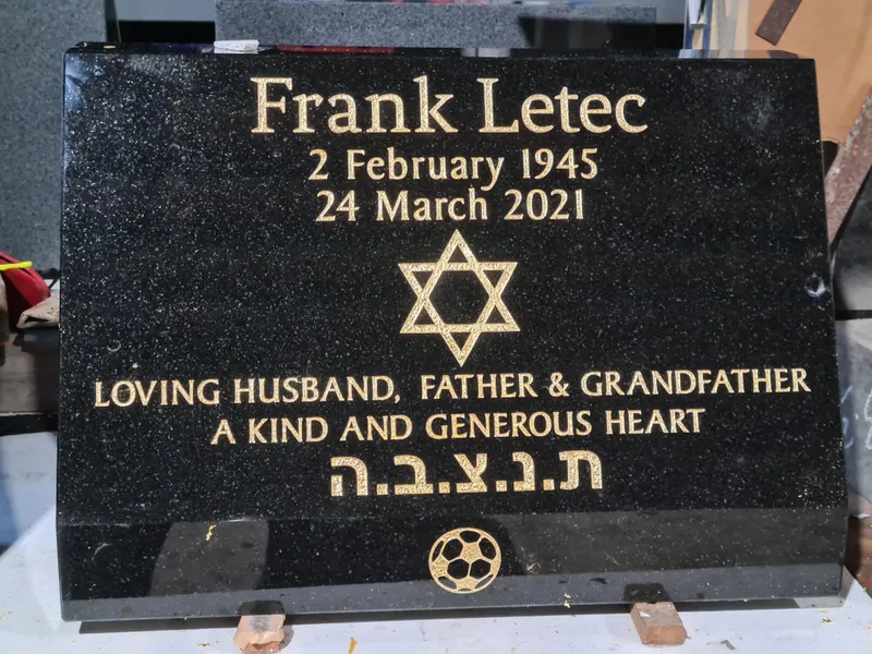Black granite plaque with gold lettering, a Star of David and Hebrew inscription