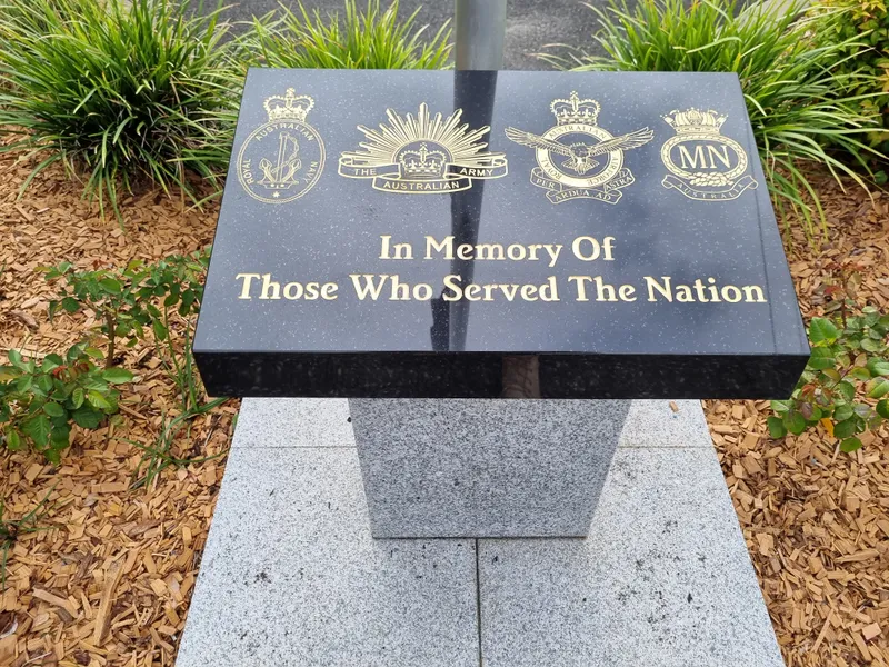 Black granite plaque honouring those who served, with armed services emblems