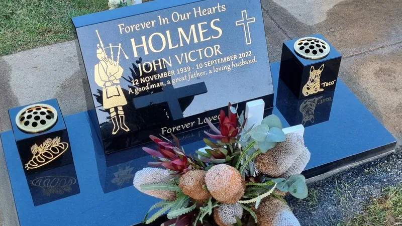 Black granite monument with an engraved bagpiper and matching vases