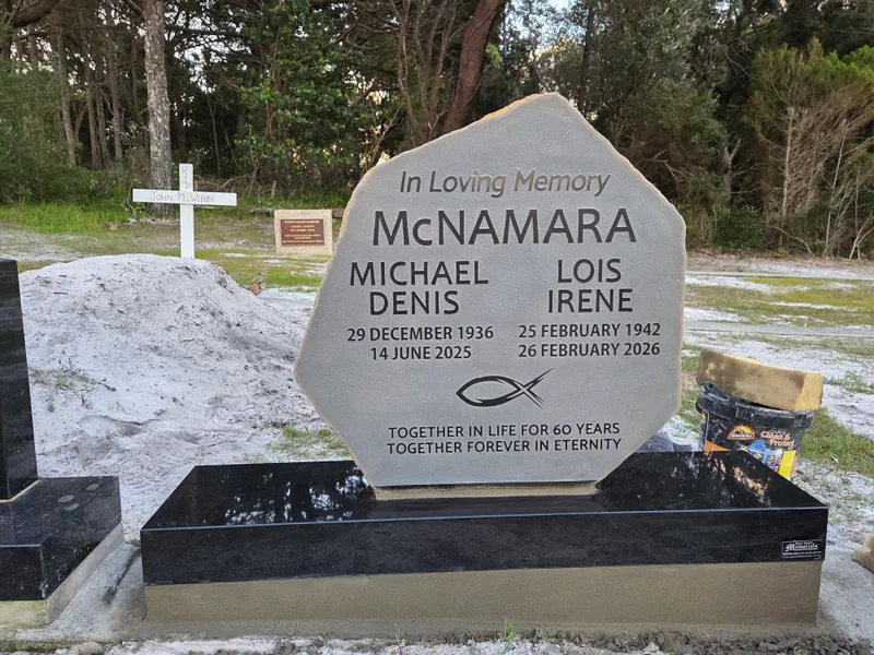 Shaped double headstone in light granite on a black granite base
