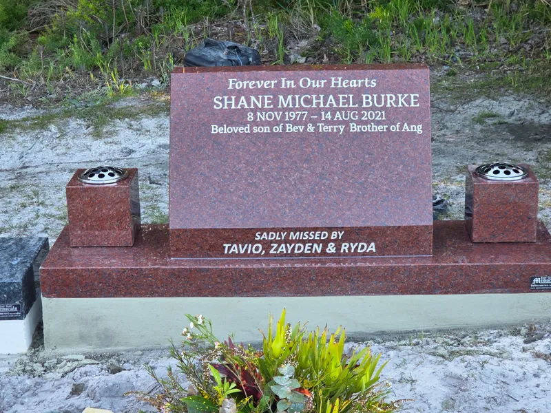 Red granite headstone with white lettering and matching red granite vases